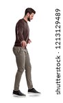 Small photo of A fit man in casual clothes stands with his arms stretched wide as he imitates tightrope walking on a white background. Careful steps. Risky steps. Life or death decision.