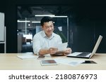 Happy and successful asian businessman reading financial document letter, boss working with documents in office, paperwork