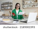 Small photo of Young latina female work with financial papers at home count on calculator before paying taxes receipts online by phone. Millennial woman planning budget glad to find chance for economy saving money