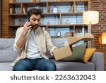 Small photo of Angry cheated man at home with phone and boxed parcel received, arguing on phone talking to online store customer support service, product delivery failed.