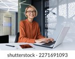 Portrait of happy and successful female programmer inside office at workplace, worker smiling and looking at camera with laptop blonde businesswoman is satisfied with results of achievements at work