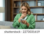 Small photo of Close-up photo. Worried senior woman mother sitting on sofa at home and holding phone. Worries about children, writes and sends messages, calls, searches, waits at home.