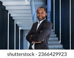 Portrait of mature and successful businessman inside office, boss smiling and looking at camera with crossed arms, african american man in business suit happy with successful achievement results.