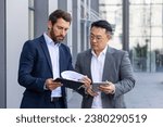 Small photo of Two male business partners outside office clock discuss financial tasks and results, serious thinking businessmen discuss financial strategy, review contracts and reports.