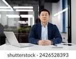 Small photo of Serene Asian businessman practicing mindfulness meditation in modern office setting to alleviate stress and maintain focus.