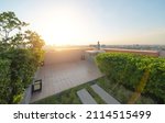 A buddha statue on sky garden on private rooftop of condominium or hotel, high rise architecture building with tree, grass field, and blue sky.