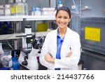Closeup portrait, young smiling scientist in white lab coat standing by microscope. Isolated lab background. Research and development.