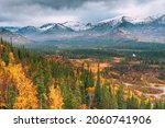 Small photo of Autumn arctic landscape. View of the misty snow-capped mountains and autumn colorful forest and tundra in the Arctic,Kola Peninsula. Mountain hikes and adventures. Austere, cold atmosphere.