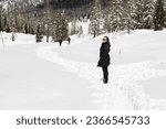 Woman standing on panoramic road on way up to Tre Cime di Lavaredo in a snowy winter day; Auronzo di Cadore; Belluno, Dolomites; Italy