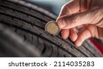 Small photo of Tire tread measuring by a two euro coin placed into the pattern of the tire.