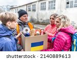 Small photo of Male NGO worker gives a box of basic food and toiletries to a family of three at the border fleeing the conflict in Ukraine.