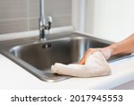 Hand of woman cleaning the kitchen counter and sink at home. Housewife doing housework concept. Closeup