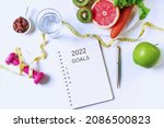 Flat lay of fruits, vegetables, dumbbell ,tape measure and a glass of water on white table background. Clean eating and exercise for good health concept. Top view, copy space