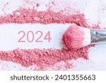 Small photo of Flat lay crushed pink blush of cosmetics product with 2024 number, copy space, top view. Happy new year, beauty, 2024 goal concept