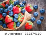 Blueberries and strawberry in wooden bowl on wooden table background