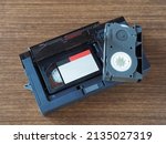 Small photo of Mini compact videocassettes, videocassette adapter on a wooden table, flat layout, closeup. Retro technology of the 90s, vintage