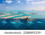 Young woman in luxury infinity pool over palm Jumeirah islands and dubai city skyline