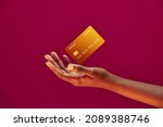 African american female hand and levitating template Bank credit card with online service on pink background