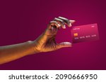 Close up african american female hand hold levitating mockup Bank credit card with online service on magenta background