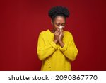 Allergic ill young african american girl blowing running nose or sneezing suffer influenza on red background