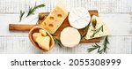 Small photo of Set or assortment cheeses. Suluguni with spice, camembert, blue cheese, parmesan, maasdam, brie cheese with rosemary and pepper. On white wooden old background. Top view. Copy space. Banner.