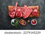 Small photo of Raw prime steaks. Variety of fresh black angus prime meat steaks T-bone, New York, Ribeye, Striploin, Tomahawk cutting board on black or dark background. Set of various classic steaks. Top view.