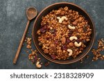 Homemade granola with greek yogurt or milk and cashews, almonds, pumpkin with dried cranberry seeds in old bowl on dark table background. Healthy energy breakfast or snack. Top view.