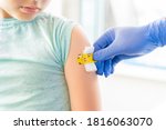 Small photo of Vaccination of little girl in doctor's office.Kids funny adhesive plaster,gauze napkin.Hand in glove.Vaccine for covid-19 coronavirus,flu,infectious diseases.Injection.Clinical trials for human,child.