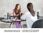 Small photo of Professional master manicurist at beauty salon. Manicure service, hands treatments, procedures for nails, fingers. Multi-colored nail polish, samples palette, tattoos, cuticle oil, gel uv lamp,gloves.