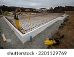 Reinforcement of foundation slab of private house. Preparation for pouring concrete foundation for house. Plinth is insulated with foam. Pavement is strewn with rubble. Horizontal.