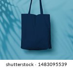 Small photo of Blue Navy Canvas Tote Bag or Goodie Bag Isolated with Palm Leaf Shadow on Wall Background