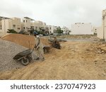 Small photo of Karachi Pakistan - 1 Sep 2023: Labor loading wheel barrow with gravel and sand at concrete making site