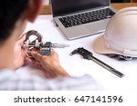 Small photo of Engineer man hand measuring bearing with digimatic micrometer with laptop in background