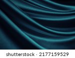 Small photo of Blue green silk satin. Soft wavy folds. Shiny silky fabric. Dark teal color elegant background with space for design. Curtain. Drapery. Christmas, valentine, anniversary, celebration concept.