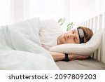 Small photo of Man sleeping on bed with smart sleep headband. Smart sleep tracker. Heartbeat monitor on head. Modern male health monitor. Cozy sleeping bed room. Wearable technology in a daily life to develop habit