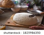 Small photo of Woman makes bread athome kitchen. She decorates risen dough with a blade.