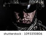 Cropped close up portrait of US special operations forces soldier, marine raider, modern combatant in helmet and glasses with dirty face after difficult military mission or battle looking at camera
