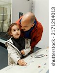 Small photo of girl in white coat and man in orange coat talking near a board in Hartlepool museum