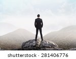 Business man standing on the top of the mountain looking at the valley. Business success concept
