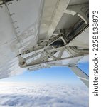 Small photo of Detailed view of flaps , high-lift devices and actuators of a general aviation airplane flying at stall speed. Strut and wing of semi-cantilever high-wing aircraft over the clouds on a sunny day.