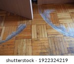 Small photo of Scratched parquet flooring in the room. Scratches, chips and dents on the floor. Parquet in need of repair. Cabinet doors are scratching the floor. Unadjusted height of furniture doors