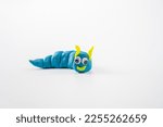 Small photo of selected focus on head plasticine play dough wriggly worm in blue and yellow isolated on a white background with copy space
