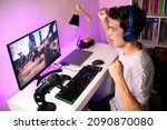Young man celebrating for winning a playing an online game. Young man playing online game on computer at home.
