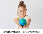 Girl with down syndrome looking at the Earth planet in her hands isolated on white background