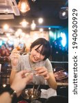 Small photo of Dinner couple date at indoor restaurant concept. Portrait happy smile young adult asian woman cheer with soju at Korean chicken meal. Foodie people lifestyle.