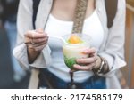 Small photo of Closeup young adult asian foodie woman hand eating asia dessert with boba. People traveling with lifestyle outdoor at China town street food market. Bangkok, Thailand