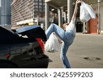 Small photo of A comical depiction of how inconvenient it is to load shopping bags into car
