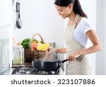 Woman standing by the stove in the kitchen, cooking and smelling the nice aromas from her meal in a pot