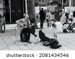 Small photo of Cardiff, Wales, August 18 2021: A black and white photograph of a male busker, street musician in Queen St. playing his guitar for shoppers.
