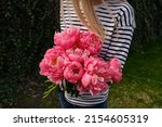 Happy woman holding pink peonies in her hands. The florist girl collected a bouquet of peonies. Delicate flowers are beautiful. A gift for the holiday, spring mood. romantic surprise